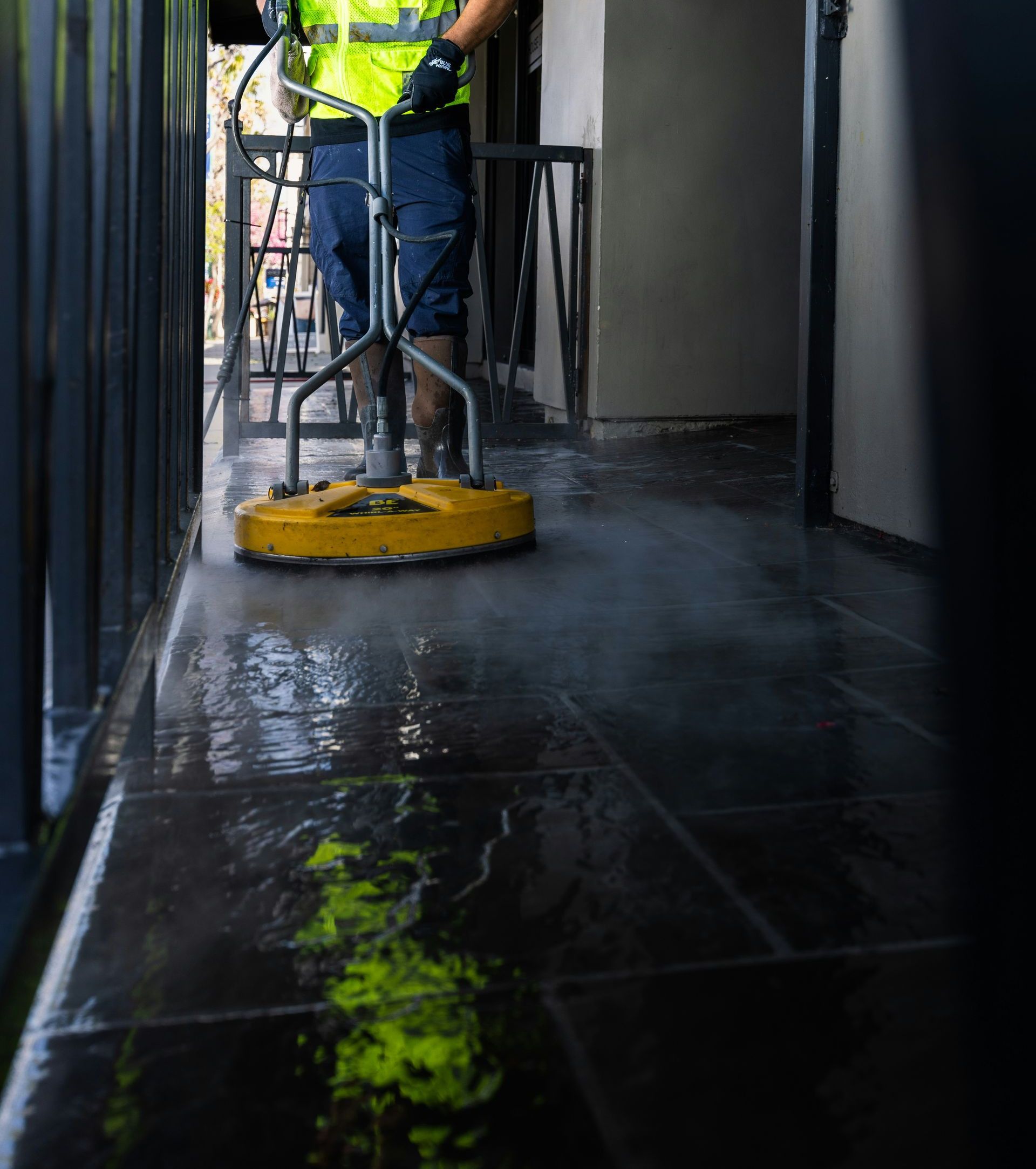a man in a yellow vest is cleaning the floor